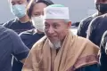 Senyuman Petinggi Khilafatul Muslimin Abdul Qadir Baraja saat Tiba di Polda Metro Jaya